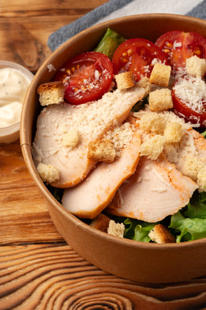 Fresh salad bowl with grilled chicken, tomatoes, and croutons served at a cozy cafe during lunchの写真素材