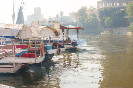 Boats navigate the river as mist envelops the banks in a tranquil morning settingの写真素材