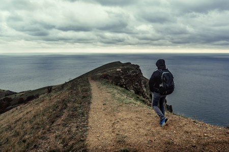 Exploring a coastal trail overlooking the ocean under a moody sky during a cloudy dayの写真素材