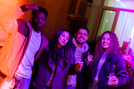 Friends enjoying a lively night out at a modern lounge with colorful lighting in the backgroundの写真素材
