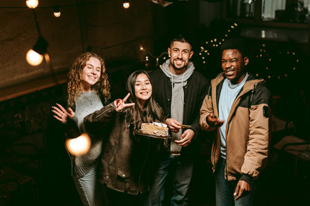 Friends celebrating together with cake in a cozy, dimly lit space during an evening gathering
