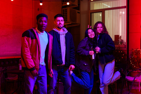 Group of friends enjoying a night out at a colorful venue with vibrant lighting in the background