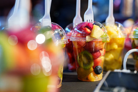 Fresh fruit cups displayed at a vibrant market during the summer afternoon with various colorful fruits ready to enjoyの写真素材