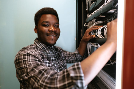 Technician organizes network cables in server room during daytime, ensuring efficient connectivity