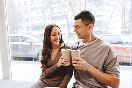 Couple enjoys warm beverages together by the window in a cozy cafe on a winter day