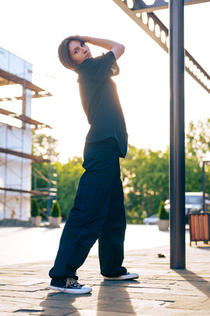 Female model poses in casual outfit during golden hour outdoors at a construction siteの写真素材
