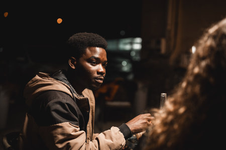 Young man engaged in a deep conversation at a night gathering outside a cafeの写真素材