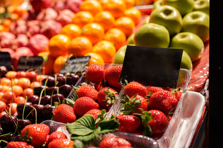 Fresh fruit display featuring strawberries, cherries, oranges, and apples at a vibrant farmers marketの写真素材