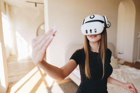 Woman explores virtual reality in modern interior during daylight hours, showcasing engagement with immersive technologyの写真素材