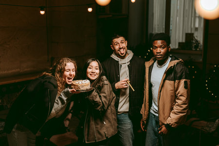 Friends celebrating with a cake during a cozy gathering in a well-lit indoor space at night