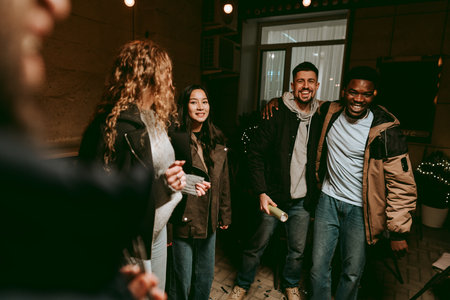 Group of friends enjoying a joyful evening gathering indoors at a cozy location with soft lighting and laughterの写真素材