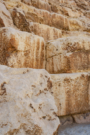 Large ancient limestone blocks form the base of a historical structure in the desert, showcasing...