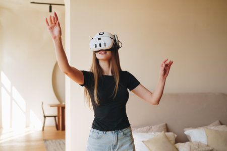 Virtual reality experience in a modern living room by a young woman engaged in immersive gameplay in the afternoonの写真素材