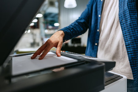 Person operating a printer to copy documents in a modern office environment
