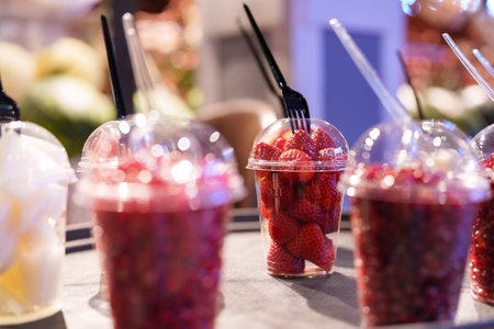 Fresh strawberries arranged in cups for sale at a market during daytimeの写真素材