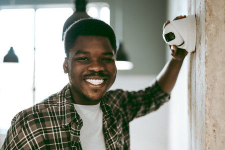 Smiling man installs security camera in modern office space during daytimeの写真素材
