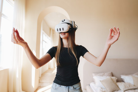 Young woman engages in virtual reality experience indoors while exploring a modern living space in natural lightの写真素材