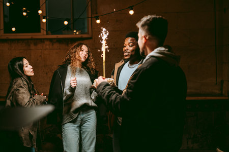 Celebrating friendship at a cozy gathering with sparklers during a warm eveningの写真素材