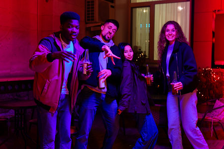 Friends celebrate together in lively indoor setting with colorful lighting at nightの写真素材