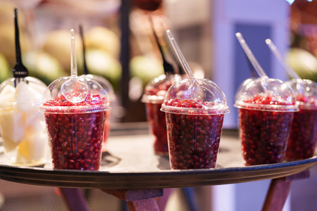 Colorful pomegranate drinks served in clear cups at an indoor market during the afternoonの写真素材