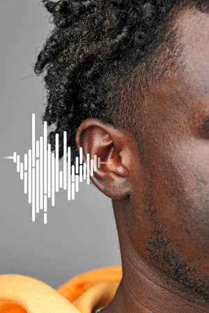 Sound waves visually represented near ear of a man wearing an orange hoodie in an urban style shootの写真素材