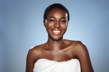 Smiling woman in towel with glowing skin against a soft blue background highlighting beauty and self-careの写真素材