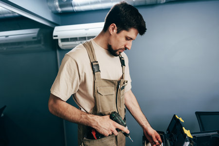 Skilled handyman works on home renovation project in modern indoor setting using power tools and organized workspaceの写真素材
