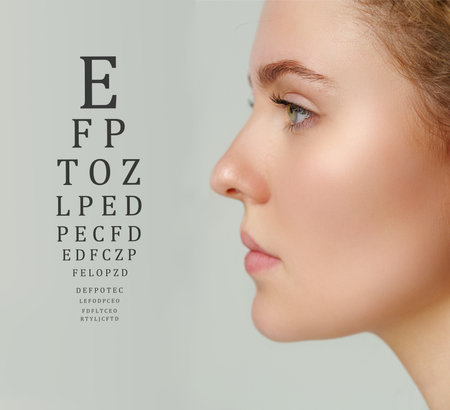 Eye examination chart displayed next to a model undergoing vision assessment in a clinical settingの写真素材