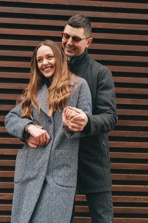 Couple enjoying a joyful moment together in urban setting with wooden background during a warm afternoonの写真素材