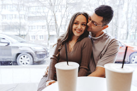 Couple enjoying a cozy moment at a cafe while sipping beverages on a winter dayの写真素材