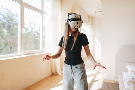Young woman explores virtual reality in a bright, modern room during a sunny afternoonの写真素材