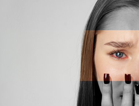 Young woman with long brown hair expressing emotion while covering half her face with her hand in a minimalist settingの写真素材