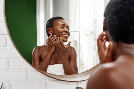 Woman caring for her skin in a bright bathroom with natural lighting and a mirror reflection during the daytimeの写真素材