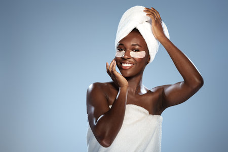 Woman applying skincare mask with a towel on her head, showcasing confidence and self-care in a serene settingの写真素材