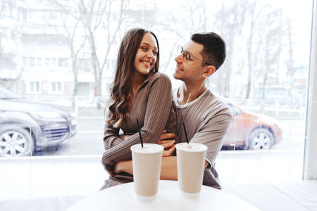 Young couple enjoying cozy time together in a cafe on a winter day while sipping warm beverages and...