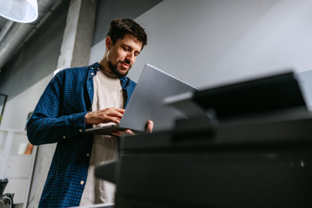 Man working on laptop in modern office space during daylight hours