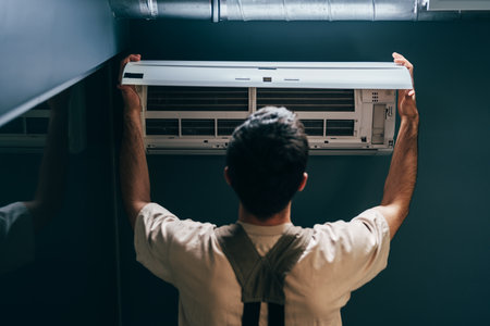 Man installs an air conditioning unit in a modern room during daylight hoursの写真素材