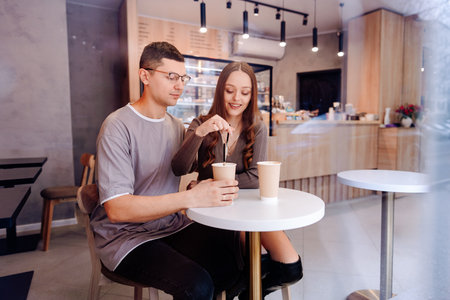 Couple enjoys coffee and conversation at modern cafe during cozy afternoonの写真素材