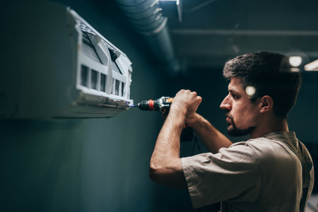 Technician installs air conditioning unit in modern indoor setting during daylight hoursの写真素材
