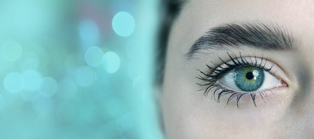 Close-up of a captivating eye with striking colors situated against a blurred turquoise backdropの写真素材