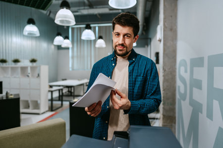 Young man organizing documents in modern office environment during daytime