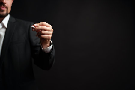 Business professional holds pen in formal attire while preparing for a presentation in an indoor setting at nightの写真素材