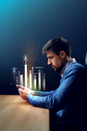 Professional man analyzing financial data on smartphone in a dimly lit office environmentの写真素材