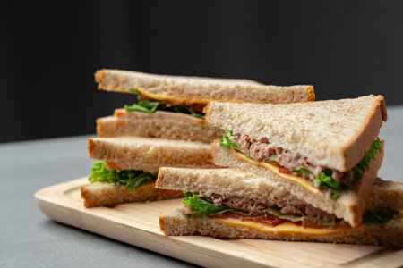 Delicious sandwiches stacked on a wooden platter with fresh ingredients prepared for a light mealの写真素材