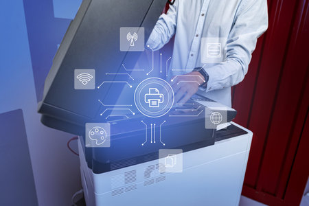 Technician working at a modern multifunction printer in an office environment during daytime,...