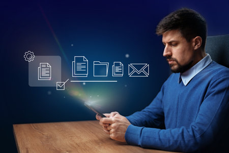 Efficient digital organization by a man using a smartphone in a modern office environment at nightの写真素材