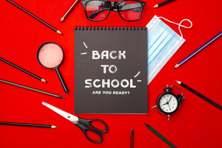 School supplies and learning essentials arranged on a vibrant red background for back-to-school...