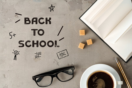 Back to school preparation with coffee, glasses, and open book on a textured surfaceの写真素材