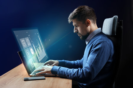 Professional man works on computer displaying financial data and graphs in a modern office setting...