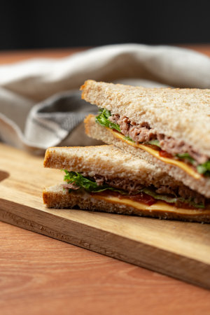 Tasty sandwich filled with savory ingredients served on wooden cutting board in a cozy setting during middayの写真素材